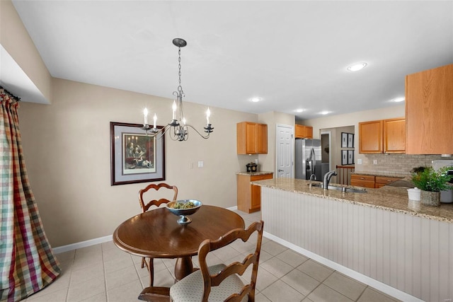 dining area with sink, light tile patterned floors, and an inviting chandelier