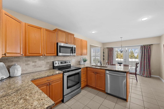 kitchen with pendant lighting, kitchen peninsula, decorative backsplash, sink, and stainless steel appliances