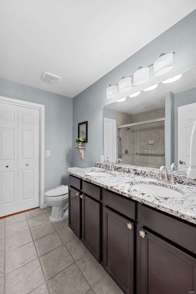 bathroom featuring toilet, tile patterned flooring, walk in shower, and vanity