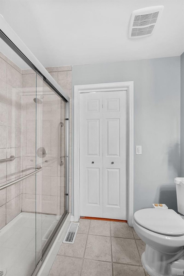 bathroom featuring toilet, an enclosed shower, and tile patterned floors