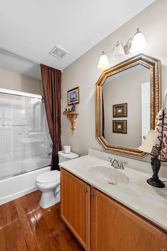 full bathroom with hardwood / wood-style floors, enclosed tub / shower combo, vanity, and toilet