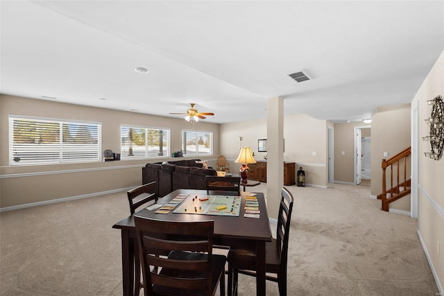 dining space with ceiling fan and light colored carpet