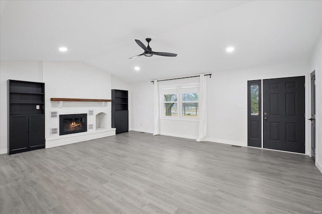 unfurnished living room with ceiling fan, a fireplace, vaulted ceiling, and hardwood / wood-style floors