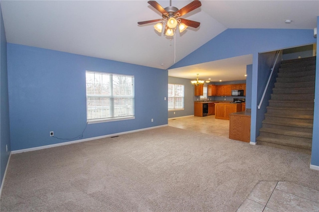 unfurnished living room featuring lofted ceiling, ceiling fan with notable chandelier, and light carpet