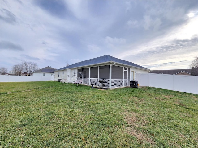 rear view of property featuring a lawn and a sunroom