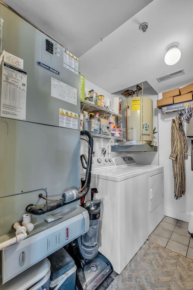 washroom with water heater, light tile patterned floors, and independent washer and dryer