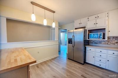 kitchen featuring white cabinets, hanging light fixtures, and appliances with stainless steel finishes