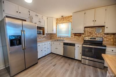 kitchen with white cabinets, hanging light fixtures, and appliances with stainless steel finishes