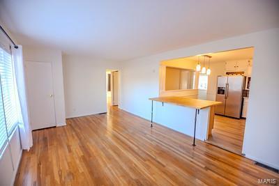 kitchen with stainless steel fridge with ice dispenser, hanging light fixtures, a kitchen breakfast bar, light hardwood / wood-style flooring, and kitchen peninsula