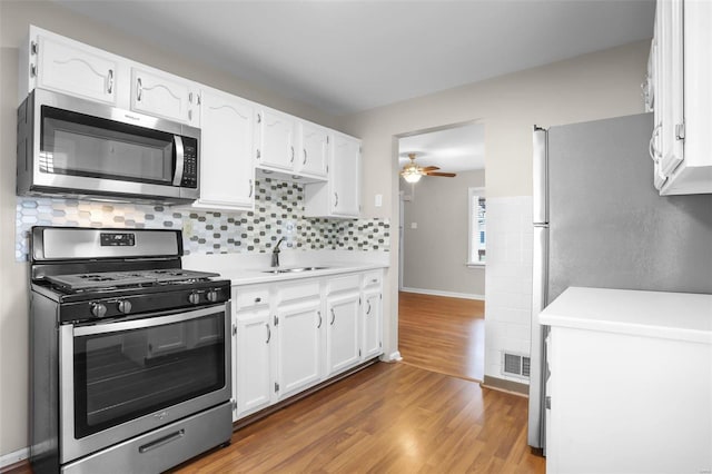 kitchen with dark hardwood / wood-style flooring, white cabinetry, sink, and stainless steel appliances