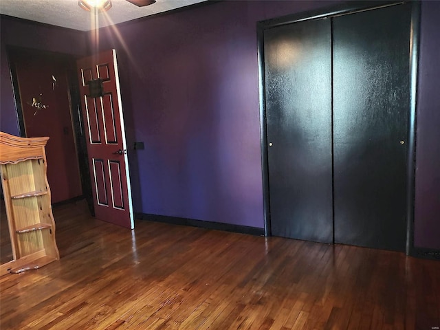 unfurnished bedroom with ceiling fan, a closet, and dark hardwood / wood-style floors