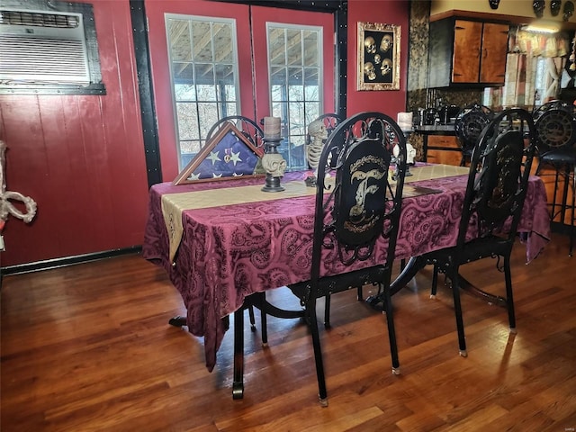 dining area featuring a wall mounted air conditioner and wood-type flooring