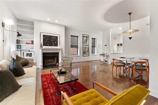 living room with built in shelves and dark hardwood / wood-style flooring