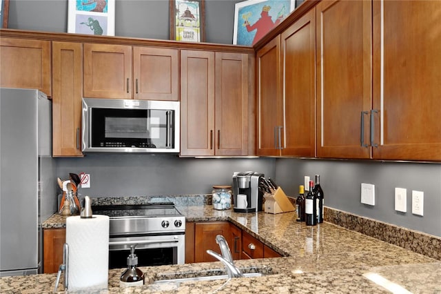 kitchen with sink, light stone countertops, and stainless steel appliances