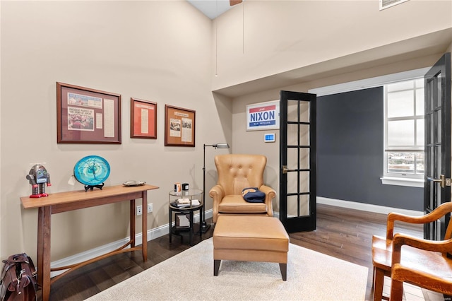 sitting room with a towering ceiling, french doors, and dark hardwood / wood-style flooring