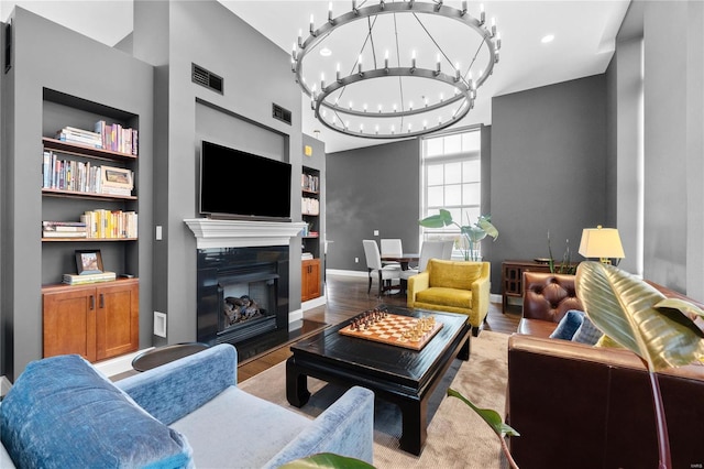 living room with light wood-type flooring, built in features, and an inviting chandelier