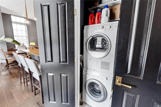 washroom with wood-type flooring and stacked washer / drying machine