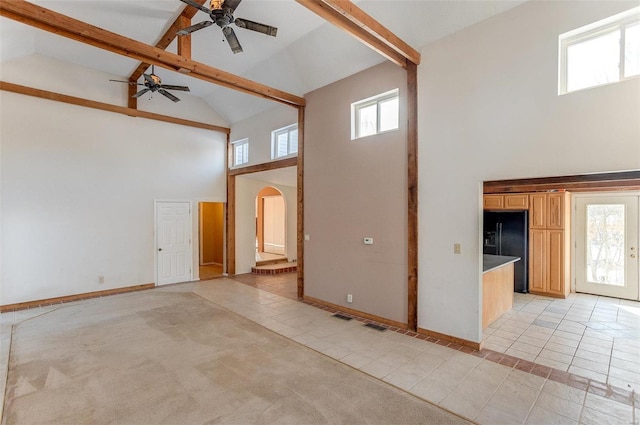 unfurnished living room with ceiling fan, beamed ceiling, light tile patterned floors, and high vaulted ceiling