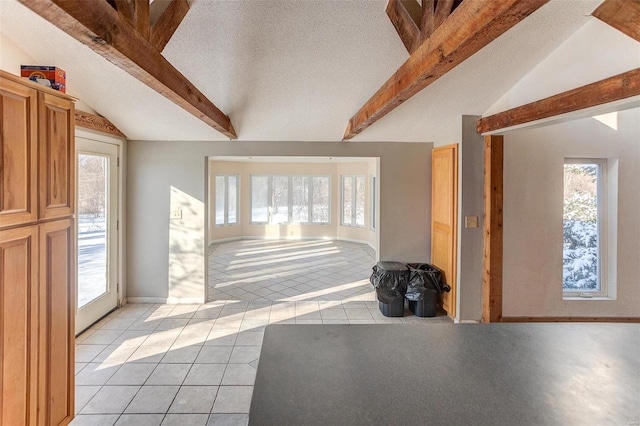 tiled entrance foyer with a healthy amount of sunlight, lofted ceiling with beams, and a textured ceiling