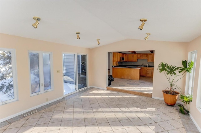 unfurnished living room with light tile patterned floors and vaulted ceiling