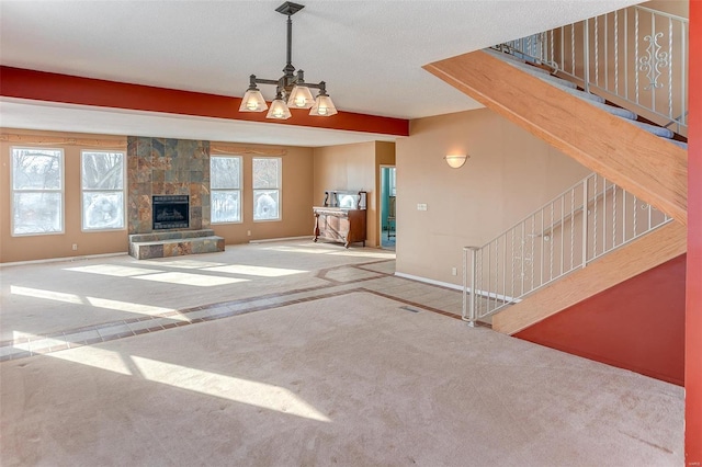 unfurnished living room with carpet flooring, an inviting chandelier, and a stone fireplace