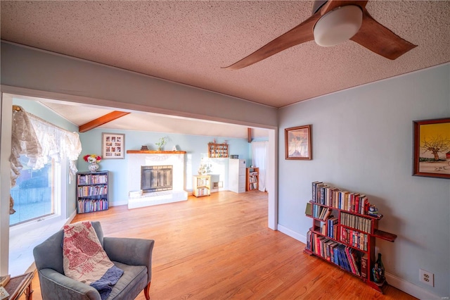 sitting room with beamed ceiling, wood-type flooring, and a textured ceiling