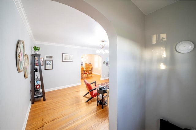 hall featuring a notable chandelier, ornamental molding, and light hardwood / wood-style flooring