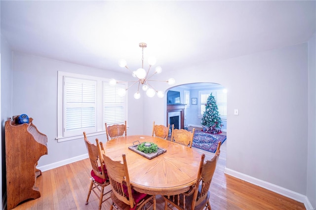 dining room with a healthy amount of sunlight, light hardwood / wood-style floors, and a notable chandelier