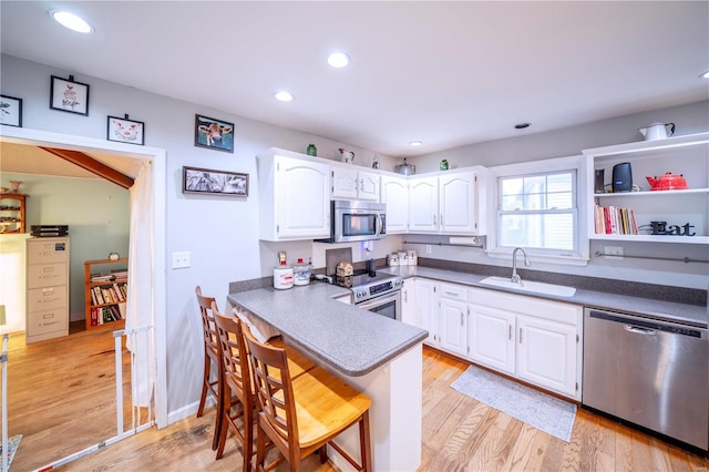 kitchen with white cabinets, a kitchen breakfast bar, sink, appliances with stainless steel finishes, and kitchen peninsula