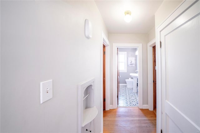 hallway featuring light wood-type flooring and baseboards