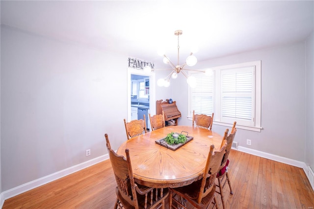 dining space featuring light wood finished floors, baseboards, and a chandelier