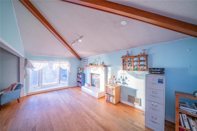 living room featuring lofted ceiling with beams, a textured ceiling, and wood finished floors