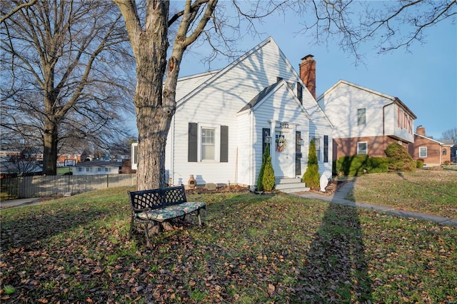 view of front of property with a chimney, fence, and a front lawn