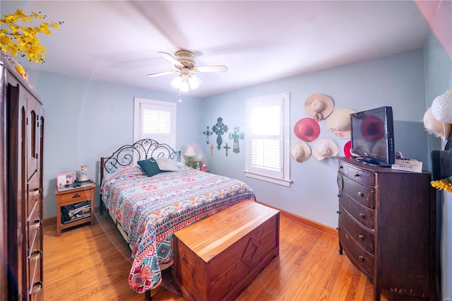 bedroom with a ceiling fan, baseboards, and light wood finished floors