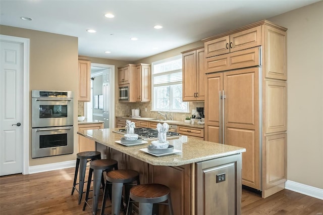 kitchen with built in appliances, light stone countertops, a kitchen island, decorative backsplash, and dark wood-style floors