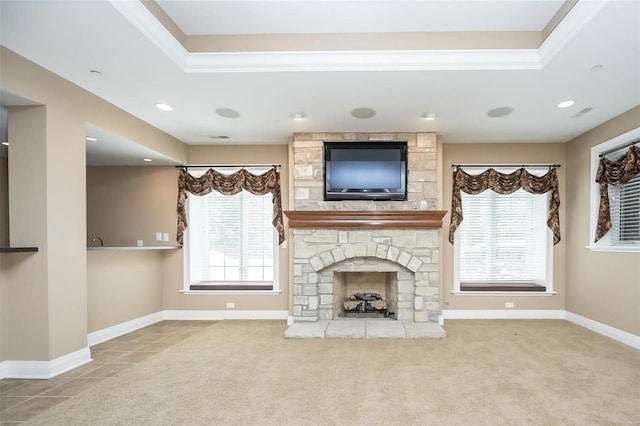 unfurnished living room with carpet floors, recessed lighting, a raised ceiling, a stone fireplace, and baseboards