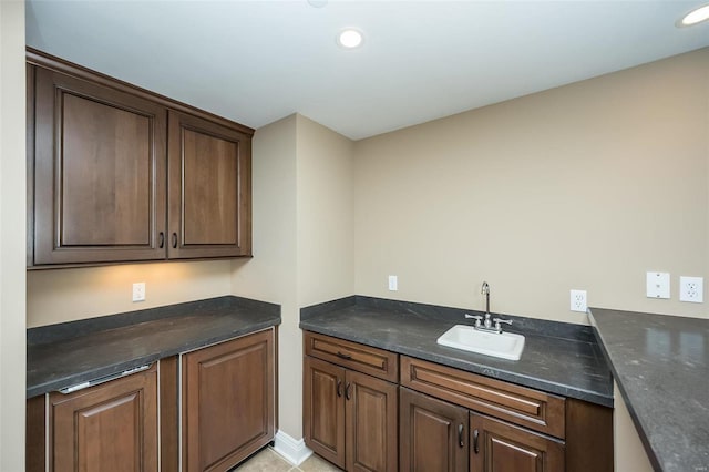 kitchen with dark countertops, a sink, dark brown cabinetry, and recessed lighting