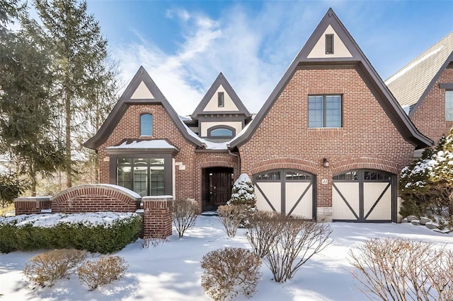 tudor house featuring a garage and brick siding