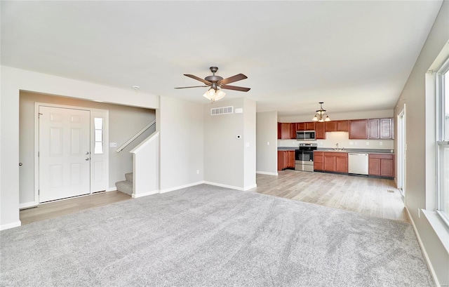 unfurnished living room featuring ceiling fan, sink, and light carpet