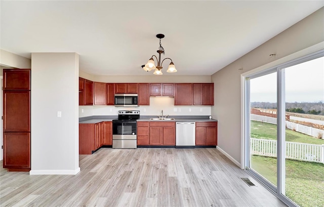 kitchen featuring sink, hanging light fixtures, stainless steel appliances, an inviting chandelier, and light hardwood / wood-style floors