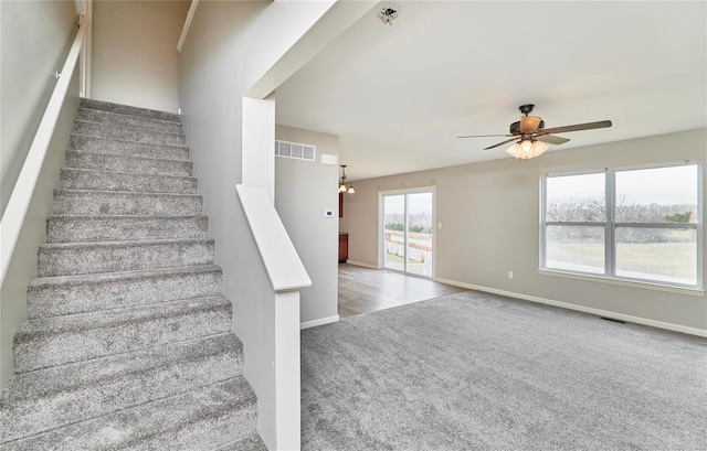 staircase with carpet floors and ceiling fan with notable chandelier