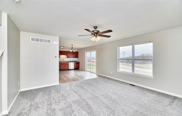 unfurnished living room with light carpet and ceiling fan