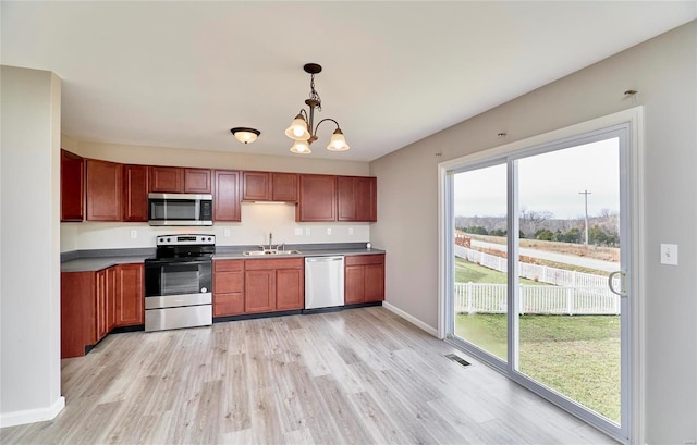 kitchen with appliances with stainless steel finishes, sink, decorative light fixtures, light hardwood / wood-style flooring, and a notable chandelier