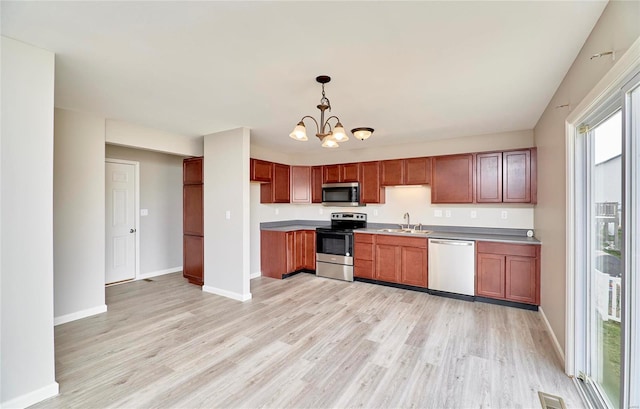 kitchen with sink, a notable chandelier, pendant lighting, appliances with stainless steel finishes, and light wood-type flooring