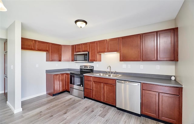 kitchen with light wood-type flooring, stainless steel appliances, and sink