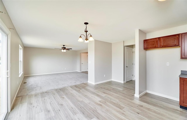 kitchen with pendant lighting, ceiling fan with notable chandelier, and light wood-type flooring