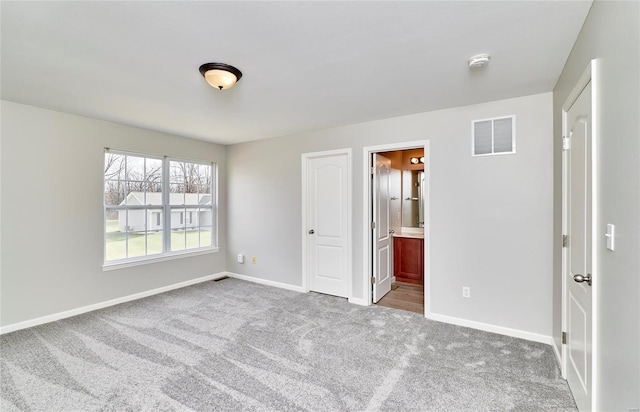 unfurnished bedroom featuring light carpet and ensuite bath