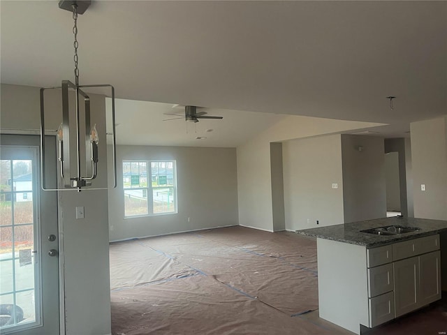 kitchen featuring ceiling fan, a healthy amount of sunlight, dark stone countertops, and sink