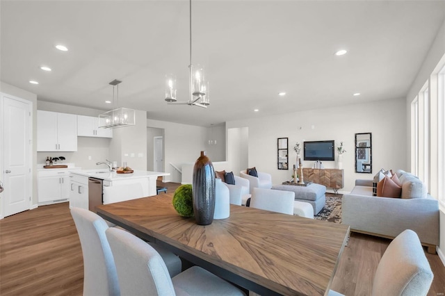 dining area with hardwood / wood-style flooring, sink, and an inviting chandelier