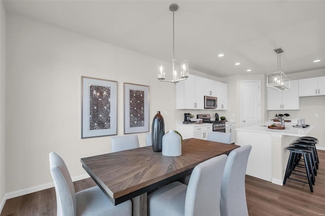 dining area with sink, dark hardwood / wood-style flooring, and an inviting chandelier